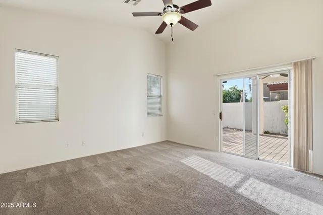 a view of an empty room with wooden floor and a ceiling fan