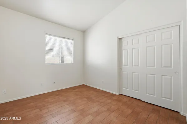 an empty room with wooden floor and closet area