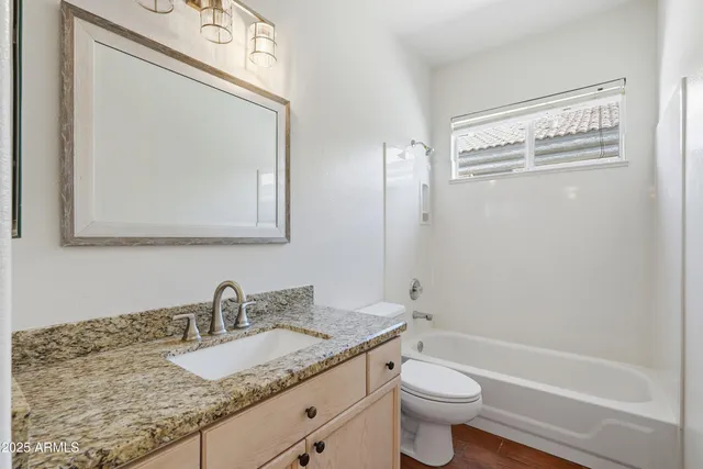 a bathroom with a granite countertop toilet a sink and a mirror