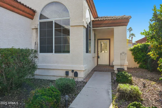 a view of house with a yard and potted plants