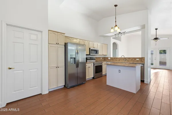 a kitchen with stainless steel appliances a refrigerator a sink dishwasher a stove and white cabinets with wooden floor