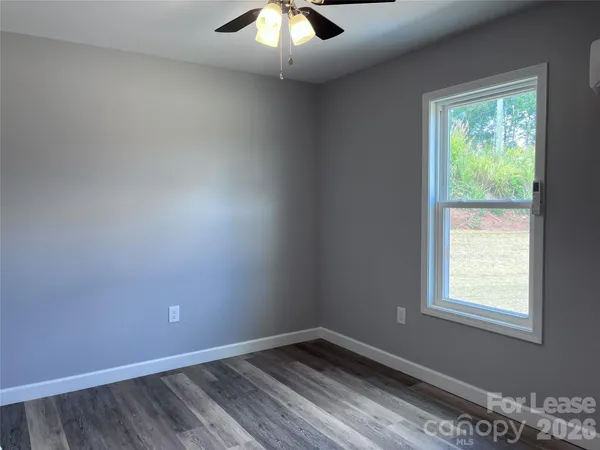 an empty room with a window and a fan