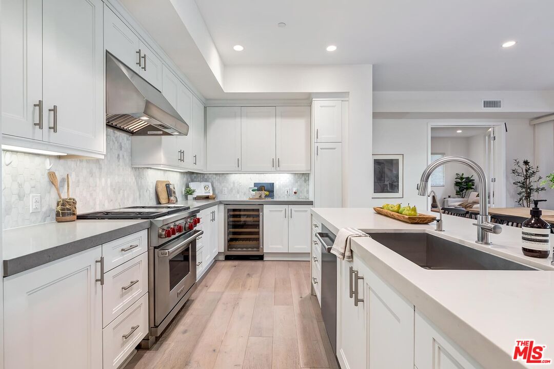 12771 Shell Place, Unit 2 Los Angeles, CA 90094 - Photo 12 of 39 a kitchen with a sink dishwasher stove and white cabinets with wooden floor