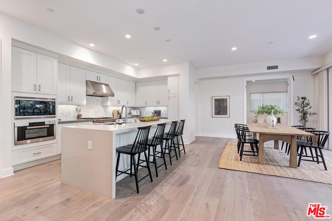 12771 Shell Place, Unit 2 Los Angeles, CA 90094 - Photo 9 of 39 a kitchen with stainless steel appliances granite countertop a stove top oven a sink a dining table and chairs with wooden floor