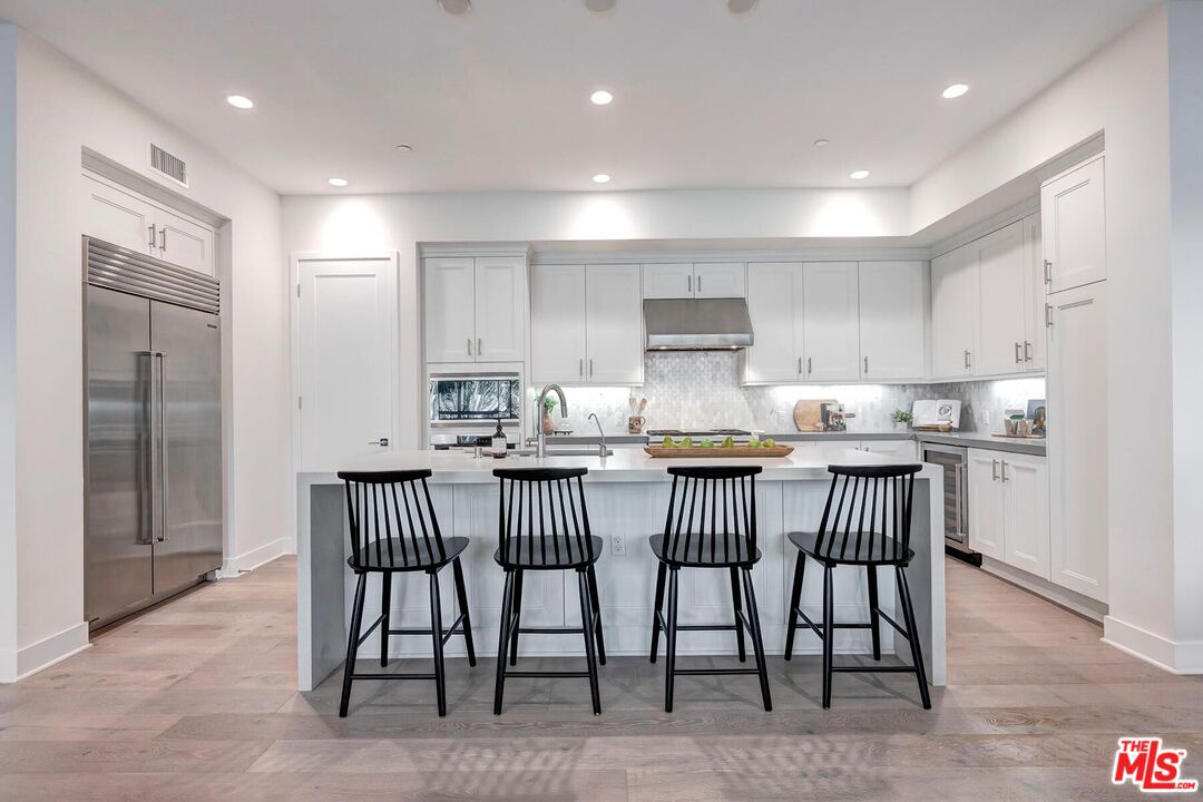 12771 Shell Place, Unit 2 Los Angeles, CA 90094 - Photo 10 of 39 a kitchen with stainless steel appliances granite countertop a table chairs sink refrigerator and cabinets