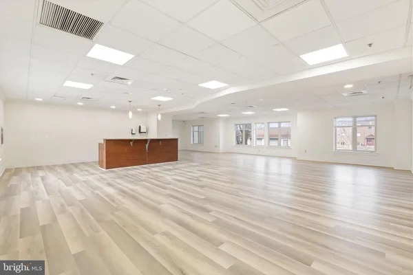 a large kitchen with kitchen island a stove a sink wooden floor and a living room view