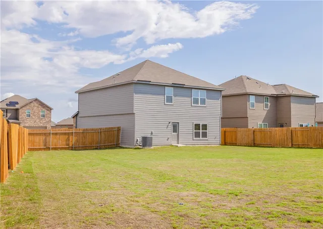 a view of a house with a yard and a large tree