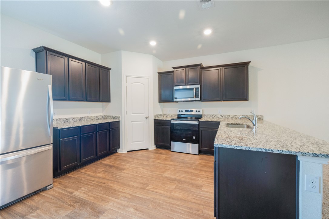 18513 Quiet Range Drive Elgin, TX 78621 - Photo 7 of 28 a kitchen with stainless steel appliances granite countertop a refrigerator stove a sink dishwasher and microwave with wooden floor