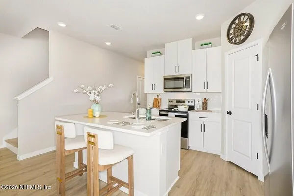 a kitchen with a sink a stove cabinets and wooden floor