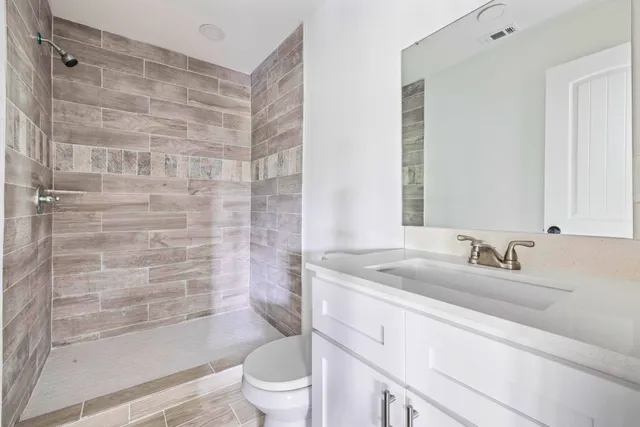a bathroom with a granite countertop sink a toilet and shower