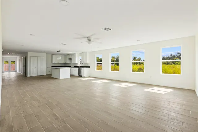 a view of empty room with kitchen and window