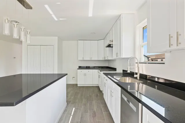 a kitchen with granite countertop a sink a stove and cabinets