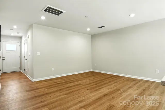 an empty room with wooden floor and natural light