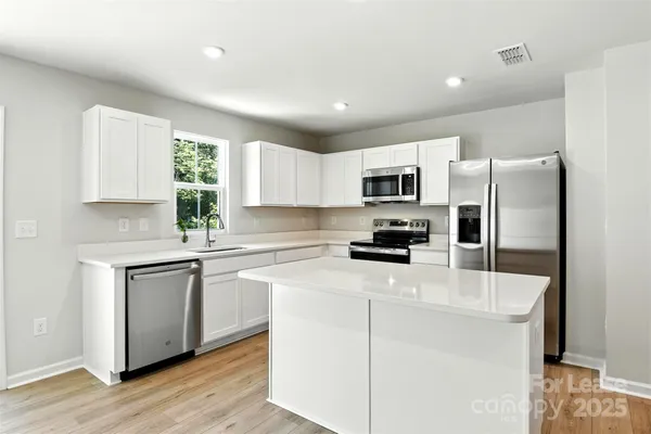 a kitchen with a refrigerator a stove top oven a sink and cabinets