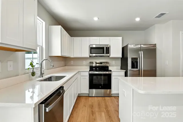 a kitchen with granite countertop a sink a counter space appliances and cabinets