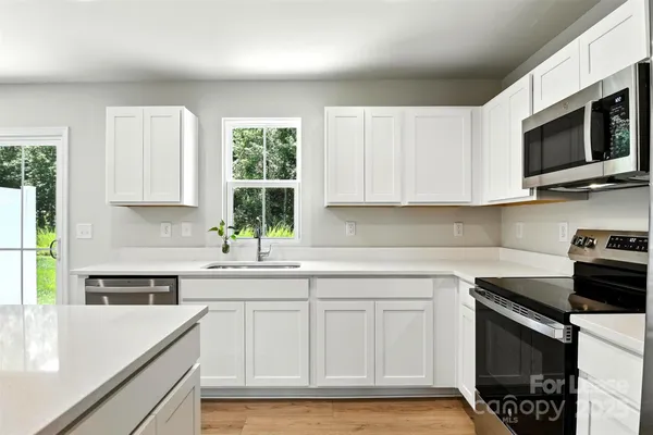 a kitchen with stainless steel appliances white cabinets and a stove top oven