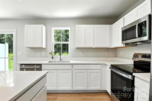 a kitchen with stainless steel appliances white cabinets and a stove top oven