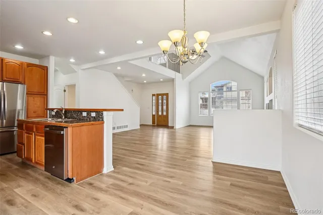 a dining room with wooden floor a chandelier a wooden table and chairs