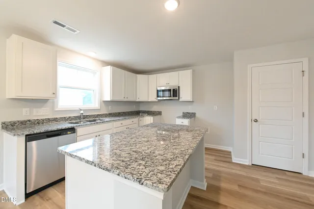 a kitchen with stainless steel appliances granite countertop a stove oven and a white cabinets