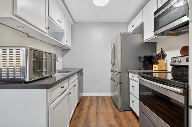 a kitchen with stainless steel appliances white cabinets and wooden floor
