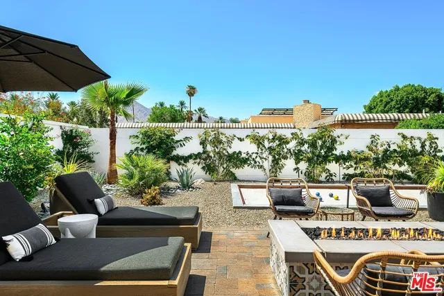 a view of a patio with couches table and chairs under an umbrella