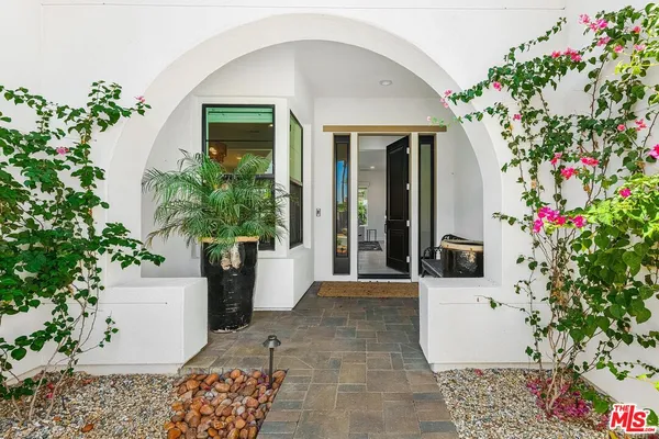 a view of a entryway door of the house with flower pots