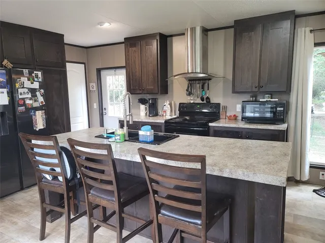 a kitchen with stainless steel appliances granite countertop a stove top oven a refrigerator a sink and a dining table with wooden cabinet