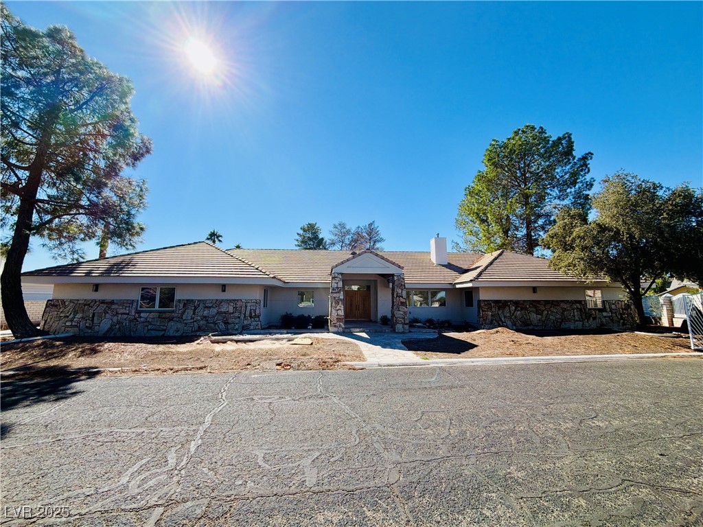 3840 South Topaz Road Las Vegas, NV 89121 - Photo 1 of 89 Ranch-style house with stone siding, stucco siding, a tiled roof, and a chimney