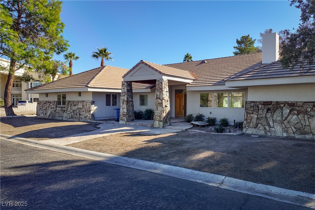 3840 South Topaz Road Las Vegas, NV 89121 - Photo 4 of 89 Ranch-style house featuring stone siding, stucco siding, a chimney, and a tile roof