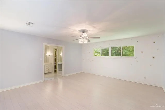 an empty room with a chandelier fan and windows