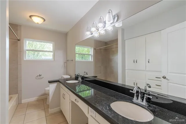 a bathroom with a granite countertop sink a toilet and mirror
