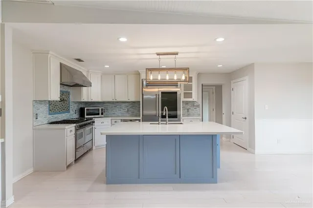 a large kitchen with a large counter top stainless steel appliances and cabinets