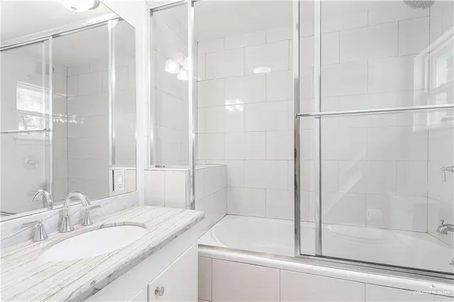 a bathroom with a granite countertop sink a mirror and a shower