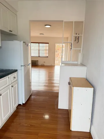 a view of a kitchen with wooden floor and a refrigerator
