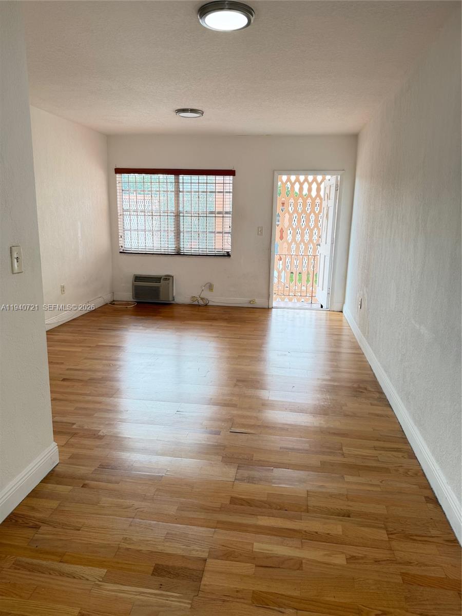 3671 Southwest 10th Street, Unit 9B Miami, FL 33135 - Photo 7 of 15 a view of an empty room with wooden floor and a window
