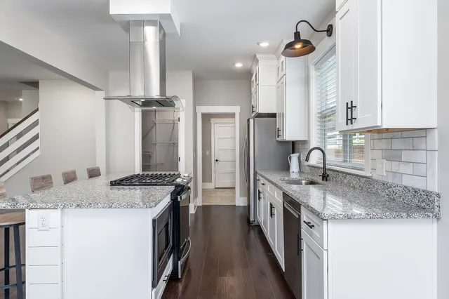 a kitchen with stainless steel appliances granite countertop a sink a stove and a refrigerator
