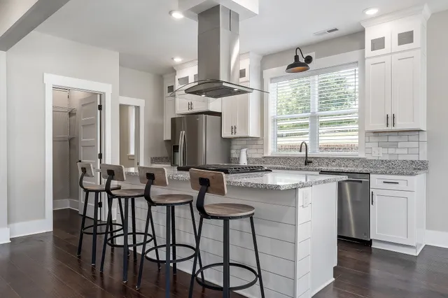 a kitchen with stainless steel appliances granite countertop a stove and white cabinets