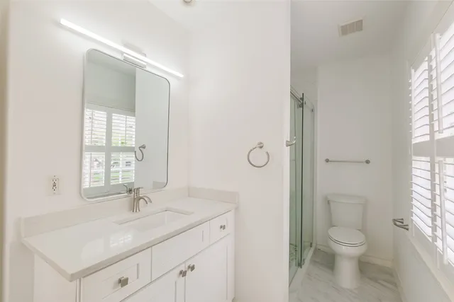 a bathroom with a toilet a sink a mirror and a window