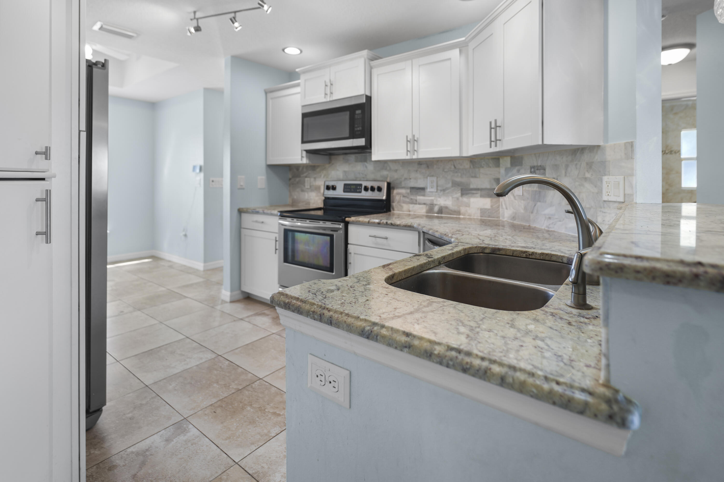 3199 Southeast Lime Tree Trail Stuart, FL 34997 - Photo 11 of 34 a kitchen with granite countertop a stove a sink and a refrigerator