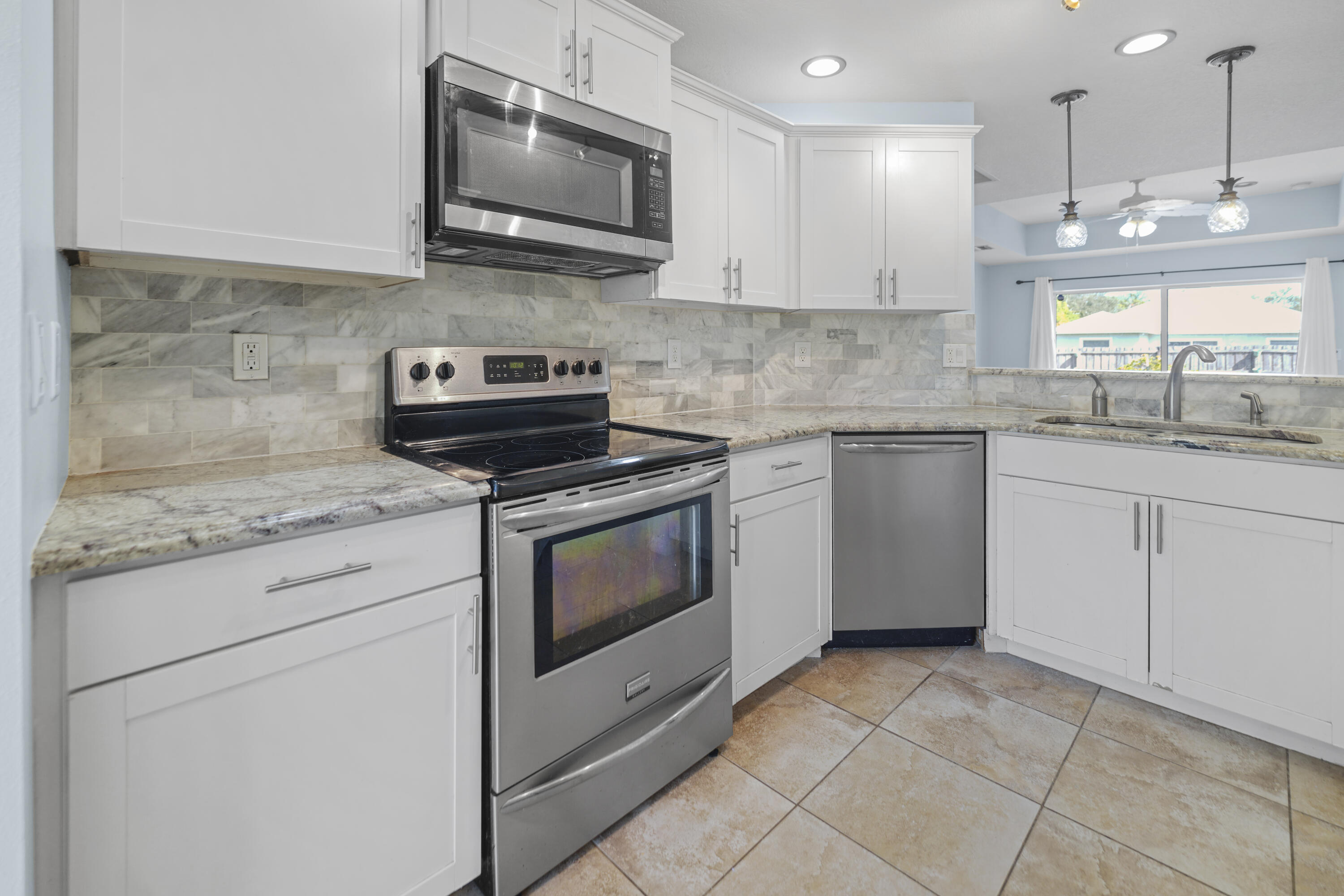 3199 Southeast Lime Tree Trail Stuart, FL 34997 - Photo 12 of 34 a kitchen with granite countertop a stove sink and microwave