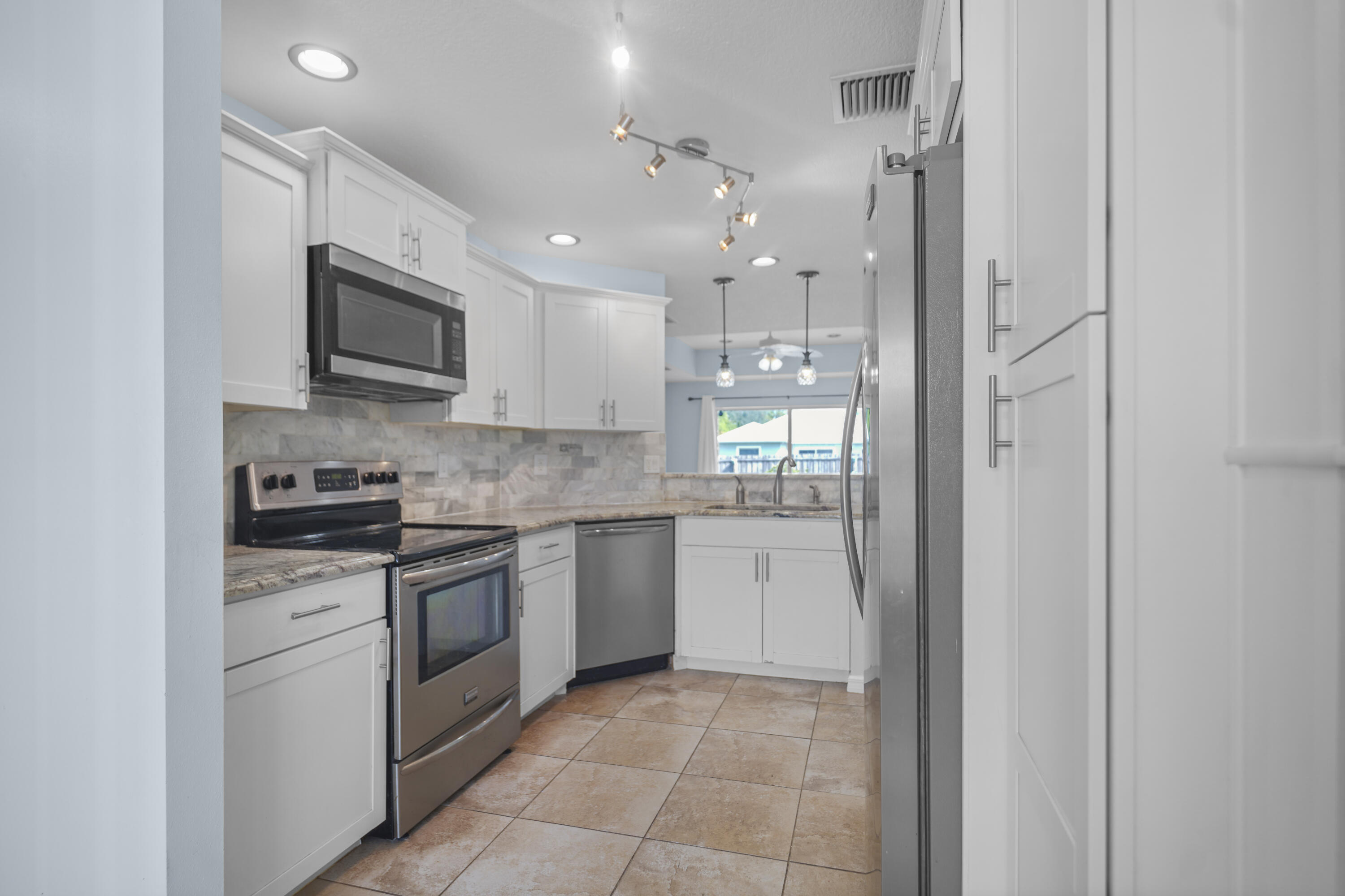 3199 Southeast Lime Tree Trail Stuart, FL 34997 - Photo 13 of 34 a kitchen with stainless steel appliances granite countertop a refrigerator and a stove top oven