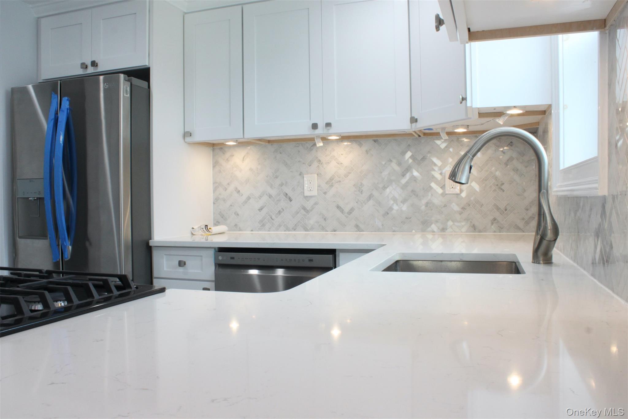 451 Warburton Avenue, Unit 3 Hastings-on-Hudson, NY 10706 - Photo 3 of 16 a kitchen with stainless steel appliances a stove a refrigerator a sink and white cabinets with wooden floor