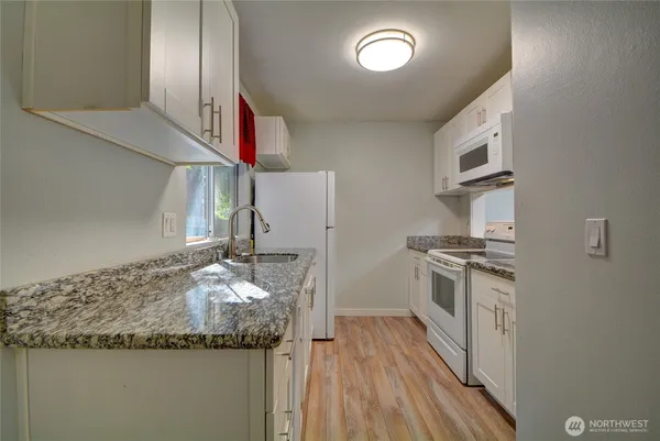 a kitchen with granite countertop stainless steel appliances and wooden floor