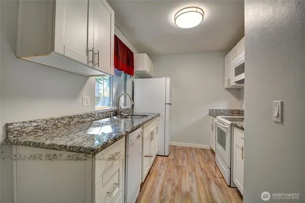 a kitchen with granite countertop a sink stove and refrigerator