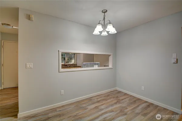 a view of empty room with wooden floor and chandelier