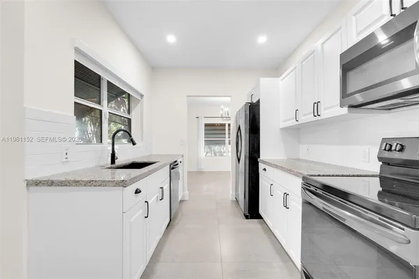 a kitchen with a sink dishwasher and white cabinets with wooden floor