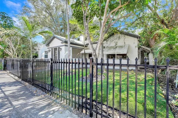 a view of a house with a small yard and a large tree
