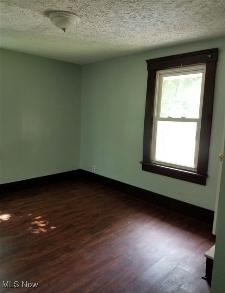 835 Berwin Street Akron, OH 44310 - Photo 14 of 18 Spare room featuring dark wood-style floors, a textured ceiling, and baseboards