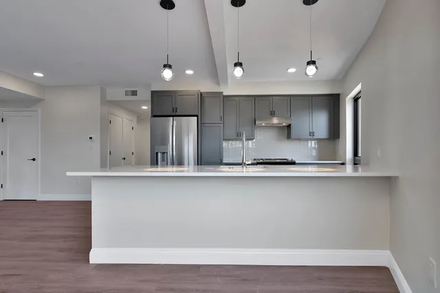 a large kitchen with granite countertop a large counter top a sink stainless steel appliances and cabinets