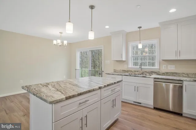 a kitchen with granite countertop cabinets a sink dishwasher and a stove with wooden floor